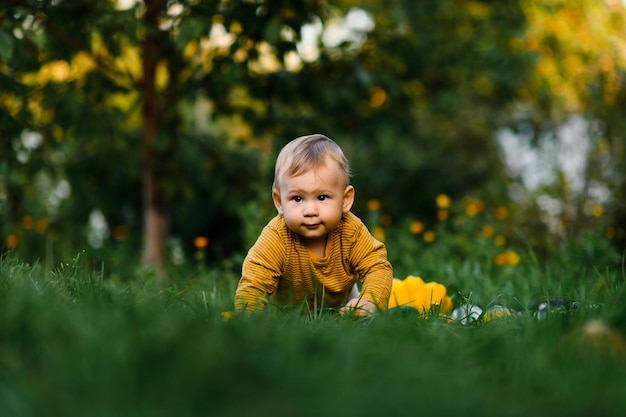 Baby boy sitting on the grass in summer day Child in trendy and cute clothes