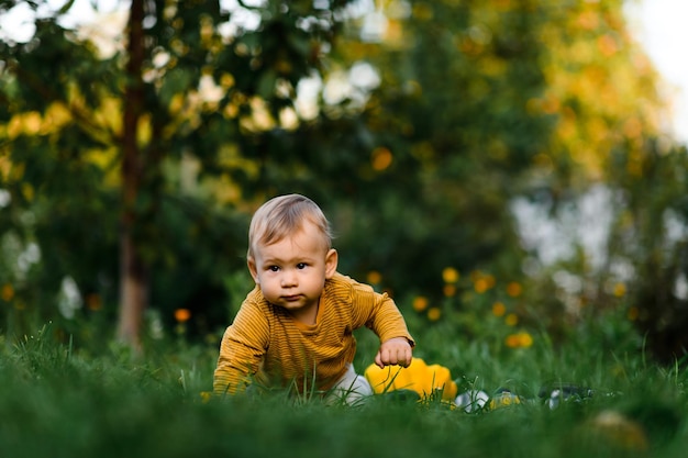 Bambino seduto sull'erba in un giorno d'estate bambino in abiti alla moda e carini