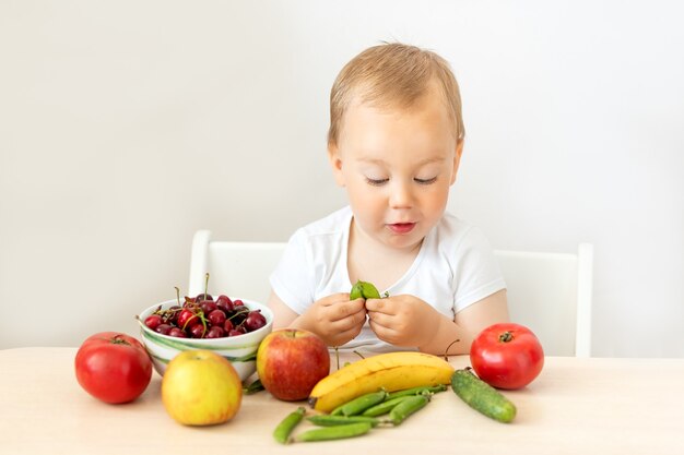 テーブルに座って果物野菜を食べる男の子