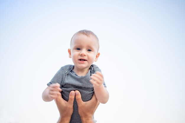 A baby boy in the sky is flying in dad's arms and smiling with happiness