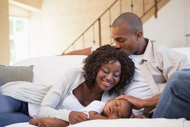 Baby boy sleeping peacefully on couch with happy parents