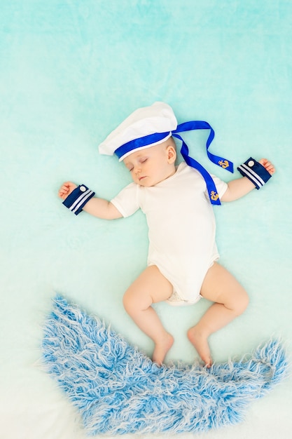 A baby boy sleeps in a sailor suit and swims on the waves in his sleep