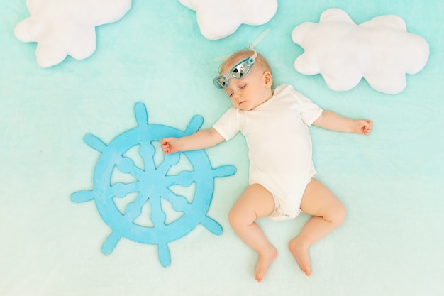 A baby boy sleeps with the steering wheel of a ship and swimming glasses