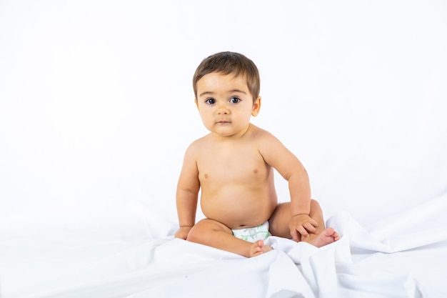 Baby boy in a studio with a white background, eight month old Caucasian newborn sitting on a cloth