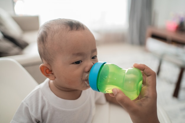 Baby boy sucking bottle of water