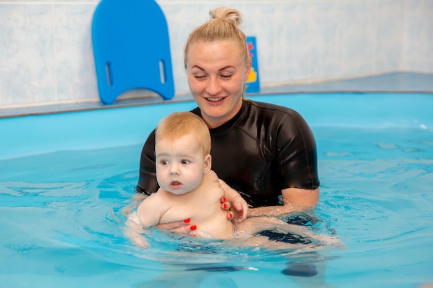 Baby boy trains to swim in the pool with a trainer