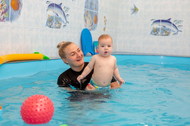 Baby boy trains to swim in the pool with a trainer