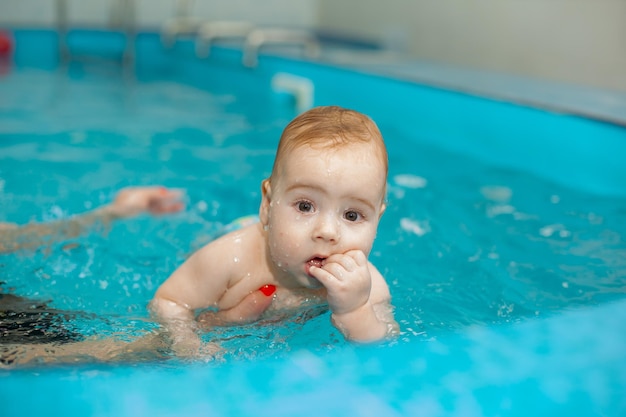 Baby boy trains to swim in the pool with a trainer