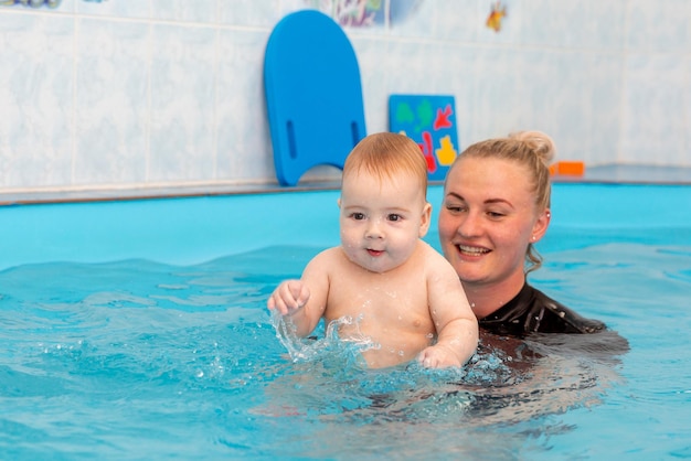 Baby boy trains to swim in the pool with a trainer