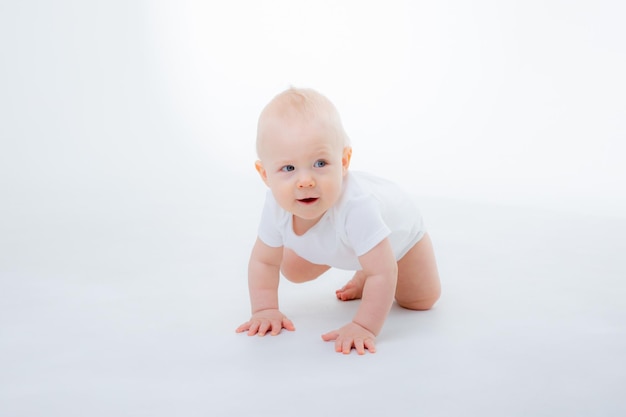 Baby boy in a white bodysuit crawling on a white\
background