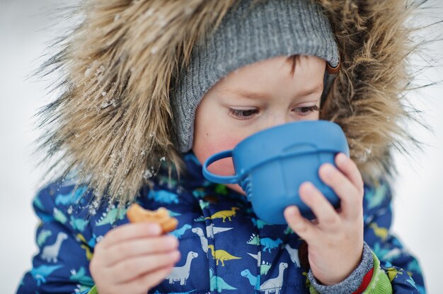 Baby boy at winter day drink hot tea.