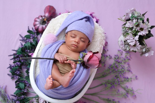 Baby boy with lavender swaddle blanket and a rose