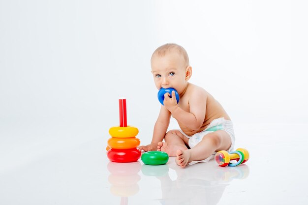 A baby boy with a multi-colored pyramid is isolated on a white background;