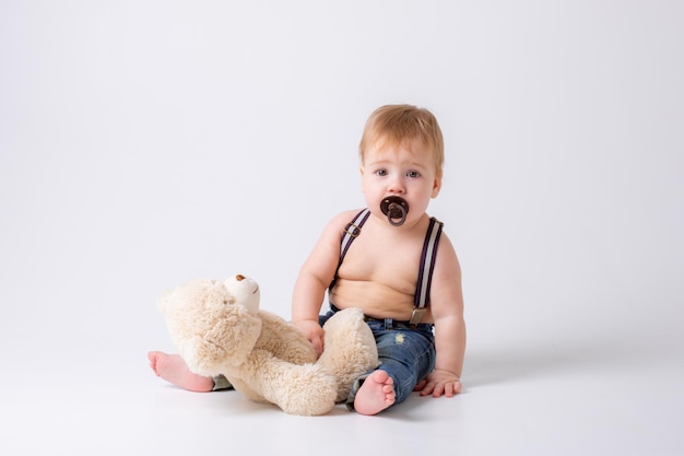 baby boy with a pacifier and jeans sitting on a white background