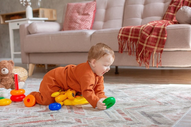 Baby boy with toys crawling on the floor at home