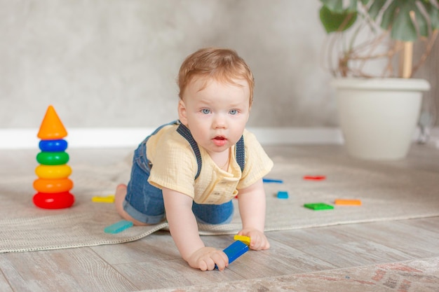 Baby boy with toys crawling on the floor at home