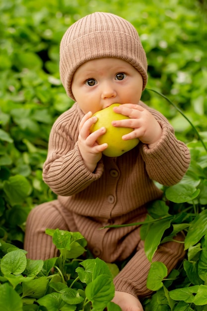 Baby in a brown hat eating an apple