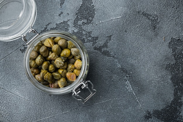 Baby capers in marinated glass jar, on gray table, top view