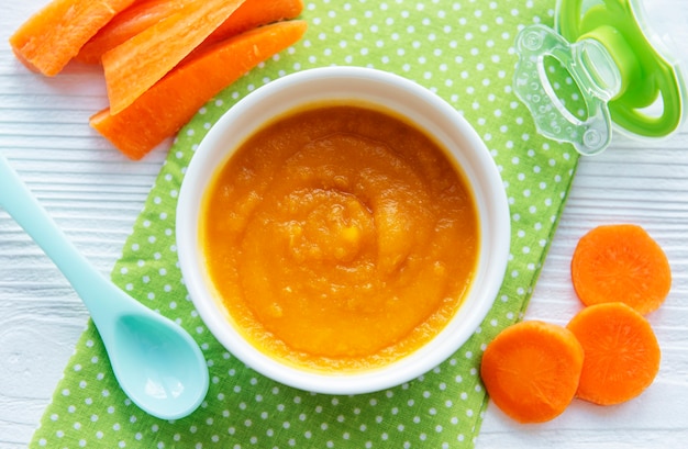 Baby carrot mashed with spoon in bowl, baby food