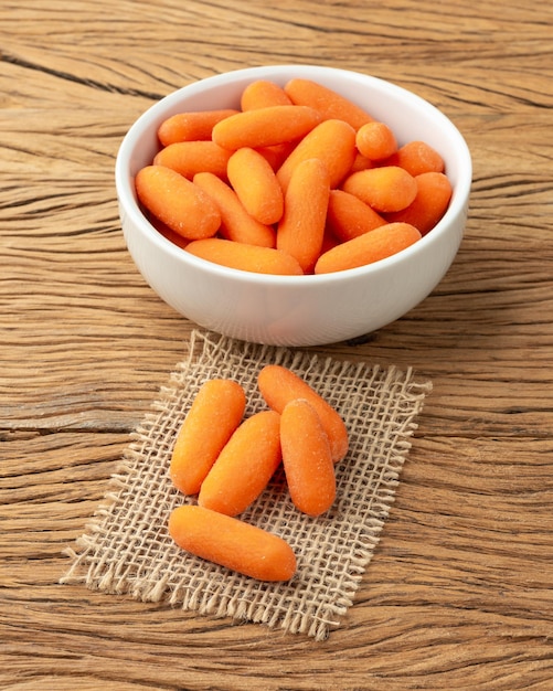 Baby carrots in a bowl over wooden table