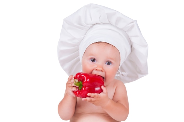 baby in a chef clothes is eating pepper