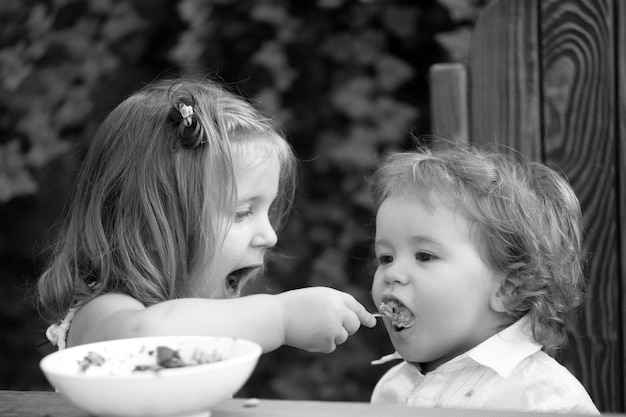 음식을 먹는 아기 아이 어린 소녀 자매가 아기에게 먹이를줍니다.