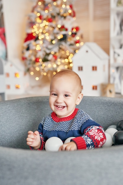 クリスマスツリーと赤ちゃん子供の肖像画。クリスマスのかわいい幼児。家族の休日の概念。子供たちは部屋を再生します。子供部屋でのクリスマス。