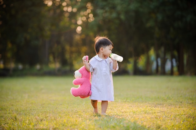 Baby child relaxing in garden and drinking milk from bottle