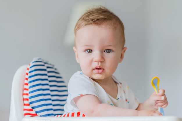 Baby child sitting in chair with a spoon