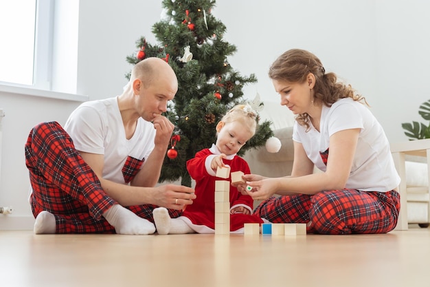 Baby child with hearing aid and cochlear implant having fun with parents in christmas room Deaf diversity and health and diversity