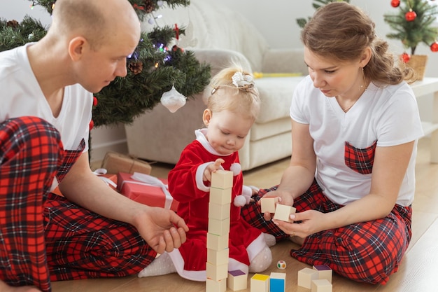 Baby child with hearing aid and cochlear implant having fun with parents in christmas room Deaf diversity and health and diversity