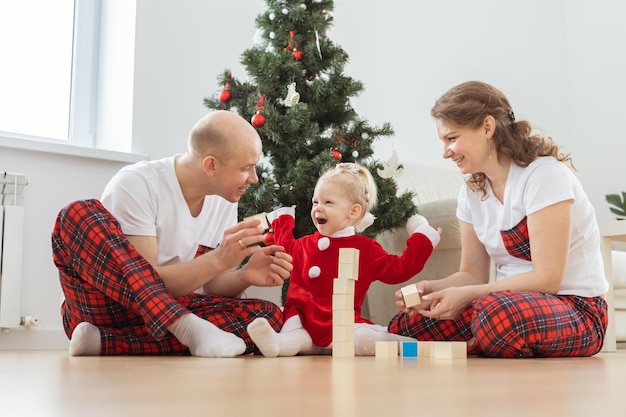 Baby child with hearing aid and cochlear implant having fun with parents in christmas room Deaf diversity and health and diversity