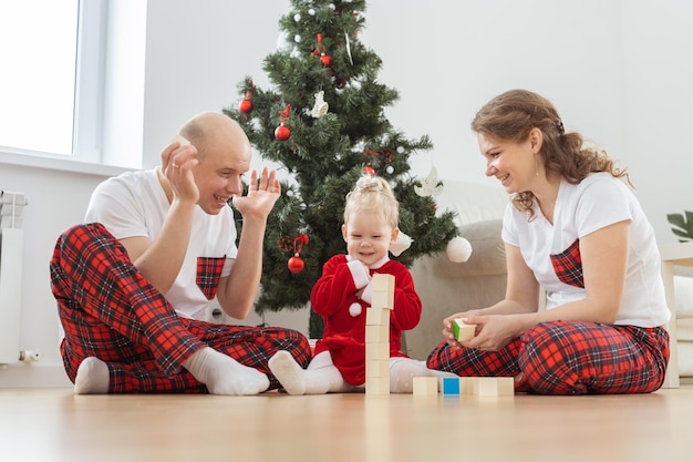 Baby child with hearing aid and cochlear implant having fun with parents in christmas room Deaf diversity and health and diversity