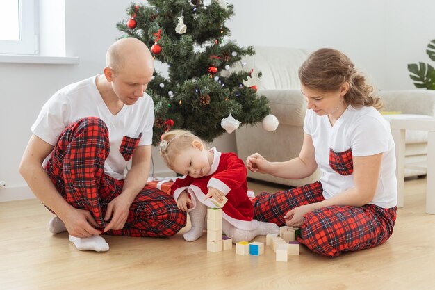 Baby child with hearing aid and cochlear implant having fun with parents in christmas room Deaf diversity and health and diversity