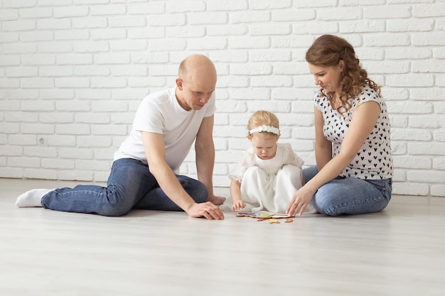 Baby child with hearing aids and cochlear implants plays with parents on floor Deaf and rehabilitation and diversity concept