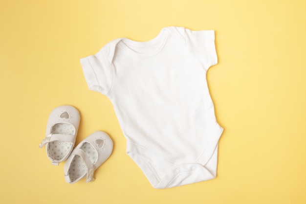 Baby clobodysuit mock-up top on yellow background for your text or logo place