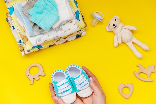 Baby clothes and accessories on the yellow background. Selective focus.