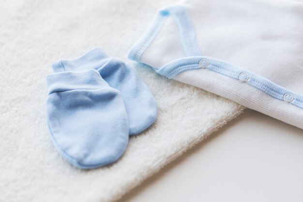 赤ちゃんの服、乳児期、母性、オブジェクトのコンセプト – 新生児用の白いカーディガン、ミトン、タオルの接写