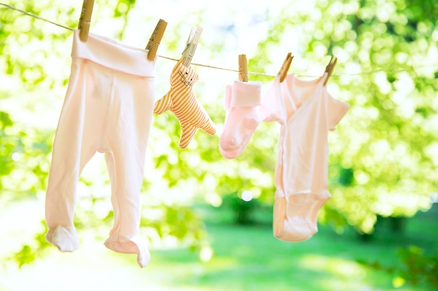 Baby clothes hanging on clothesline outdoor Child laundry hanging on line on green background