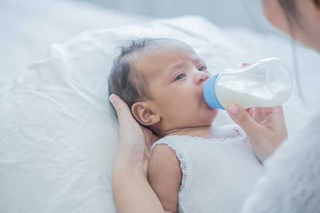 Baby consumeert melk uit de fles die door moeder wordt gevoed en raakt haar kind teder aan