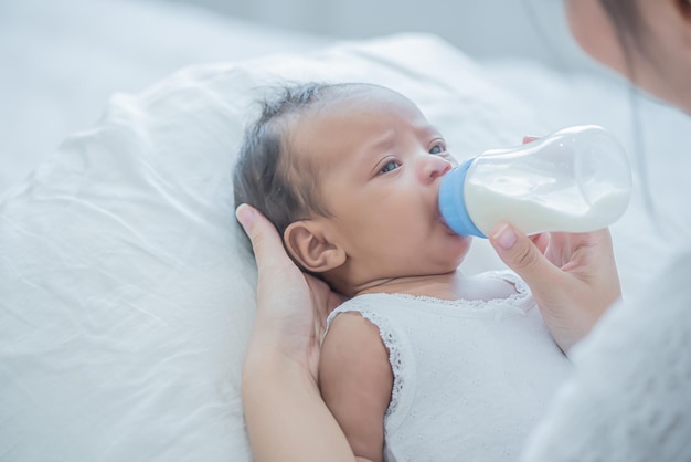 Baby consumes milk from bottle fed by mother and touches her child with tenderness