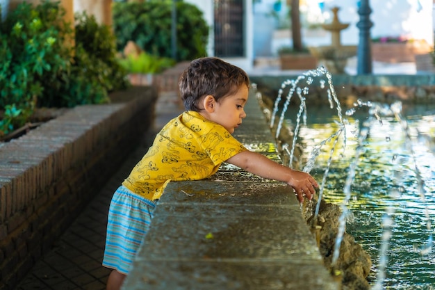 Un bambino che si rinfresca dal caldo nella fontana nel comune di mijas a malaga, in andalusia