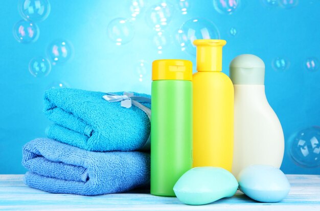 Baby cosmetics towels and soap on wooden table on blue background