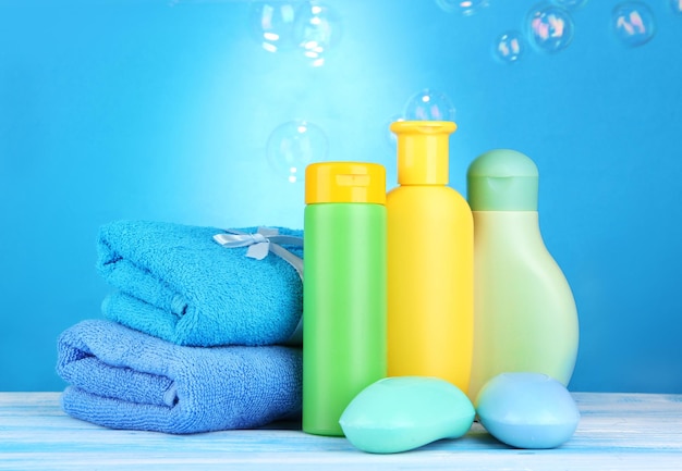 Baby cosmetics towels and soap on wooden table on blue background