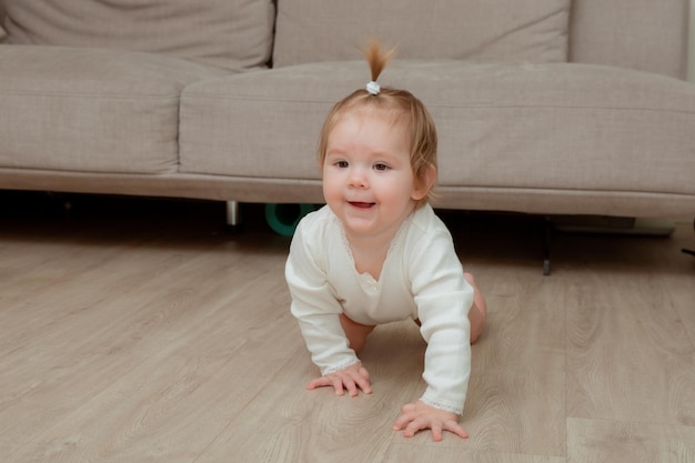 A baby crawling on the floor with a couch behind her