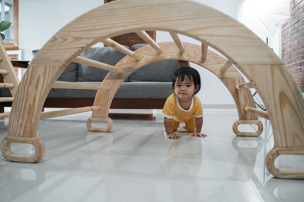 Baby crawling past under the pikler climbing toys in the house