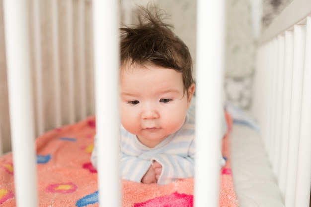 Baby in the crib. funny baby in a white canopy bed. children's room interior and bedding for children