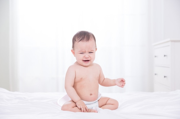 Photo baby crying on bed in bedroom