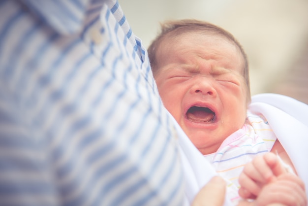 Bambino che piange in un abbraccio materno. concetto sano neonato e infantile.