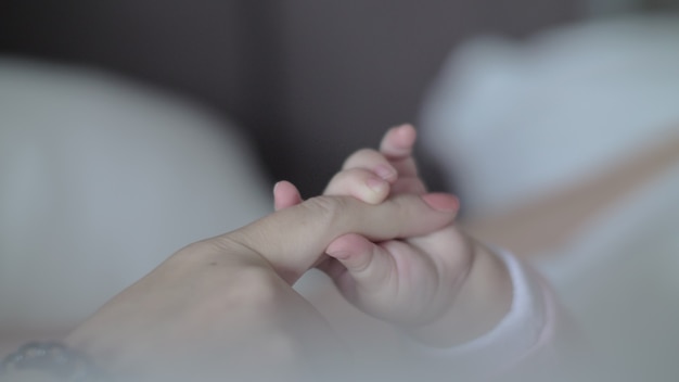 ママの指を保持している赤ん坊の娘